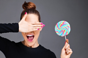 A picture of a young woman posing with a lollipop over gray background